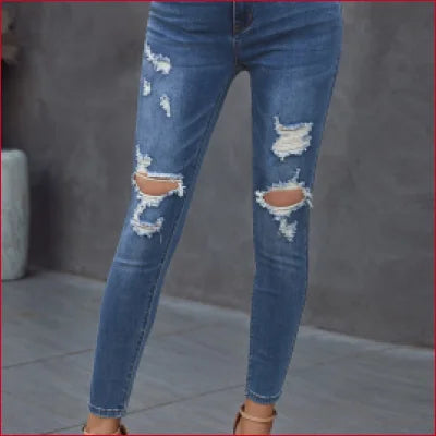 Pair of distressed dark blue figure-sculpting denim jeans with ripped knees and frayed edges