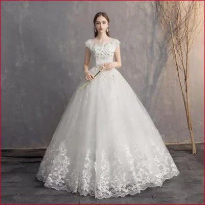 Ornate off white bridal dress gown featuring lace details and cap sleeves