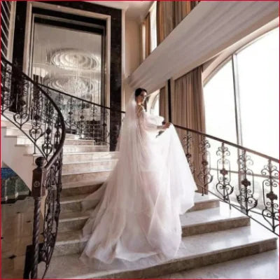 Bride in a flowing white sleeves wedding dress with detachable puffy sleeves on staircase