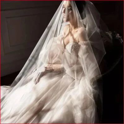 Bride in elaborate white wedding gown with detachable puffy sleeves and long veil