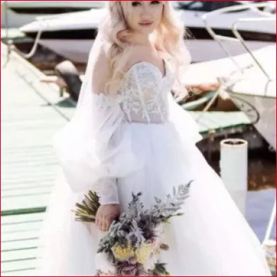 Bride in a strapless white gown with detachable puffy sleeves and a floral bouquet