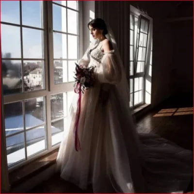 Bride in a flowing white wedding gown with detachable puffy sleeves and bouquet