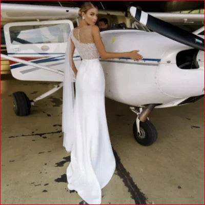 Small single-engine propeller aircraft with white and blue stripes next to a mermaid bridal gown