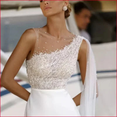 Elegant white mermaid bridal gown with sheer embellished bodice and sleeveless design