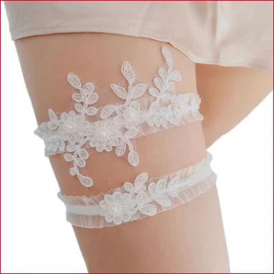 Lacy white bridal garter set featuring double white lace worn on a thigh