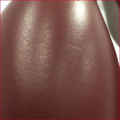 Smooth, shiny surface of dark brown skin highlighting Red Wine Faux Leather Leggings